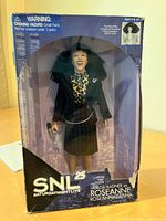 Front view of boxed Roseanne Roseannadanna doll with SNL 25 branding