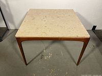 square coffee table front view showing marble top and walnut legs