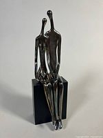 Front view of sterling silver on wax sculpture seated couple on wood block base