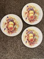 Front view of three plates displaying fruit artwork