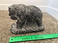 Left side view of stone bear with fish beside ruler showing scale