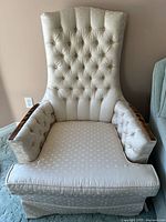Cream tufted high-back chair with polka-dot fabric and wood arm caps