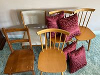 Front view of five assorted wooden chairs with throw pillows