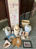 Shell-themed framed art, wastebaskets, shells, bathroom accessories and book grouped together