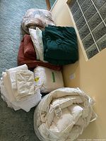Group of stacked comforters, blankets and sheets showing quantity and variety
