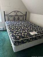 Full view of bed showing wrought iron headboard, mattress and box spring