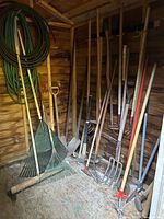 Overall view of long-handled tools and hoses in shed