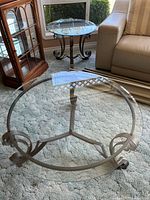 Large round glass coffee table and smaller matching side table, showing metal scroll legs