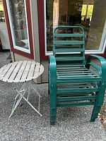 stacked green metal chairs beside white folding side table