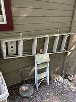 Wooden ladder section and small folding step stool leaning against wall