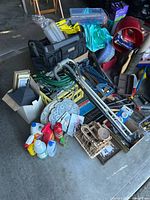 Overall view of pile showing Craftsman tool bag, garden hose, tools, frames, stepping stones and cleaners