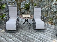 two lounge chairs and wicker side table on deck