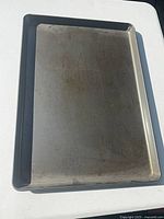 Top view of dark gray rimmed baking sheet showing interior surface wear and discoloration
