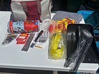 Entire kit laid out with bag, shovel parts, rope, gloves, shop towels, siphon pump, HELP sign, flashlight, gray blanket