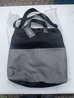 Front view showing black nylon body, gray perforated panel and attached tag
