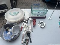 Overall lot on table showing bakeware, utensils, glass dishes, cake carrier lid