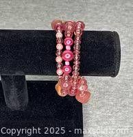 Pink beaded spiral bracelet displayed on black stand