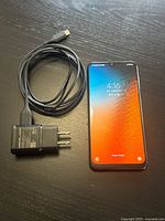 Front of Samsung smartphone powered on alongside charger and cable