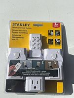 Front of sealed Stanley W31166 wireless remote outlet system showing remote and three receivers