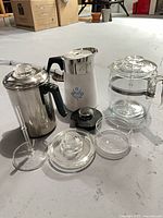 Group view of three coffee pots and associated glass parts