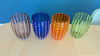 Four colored dotted glass tumblers standing side-by-side on a table