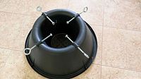Top view of black plastic tree stand showing overall form and four eye-bolt screws