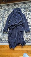 Front view of navy bathrobe with belt on rug