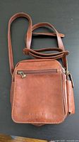 Front view of brown Dionigi leather crossbody bag with strap