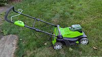 Side view of Greenworks mower showing handle and wheels on grass