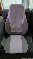 Front view of HoMedics massage cushion on chair showing backrest, seat pad and attached controller