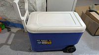 Side view of blue Igloo Wheelie Cool 38-quart cooler showing wheels and tow handle