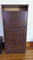 Front view of brown three-door shoe cabinet with open top shelf