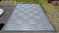 54 grey IKEA Runnen interlocking deck tiles arranged on pavement with edges visible