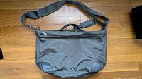 Front view of Longchamp grey nylon shoulder bag showing zip-top closure, handles, adjustable strap, leather corners