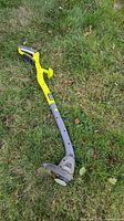 Full view of Ryobi cordless string trimmer/edger lying on grass