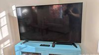Front view of Samsung 50-inch TV on stand with two remotes visible
