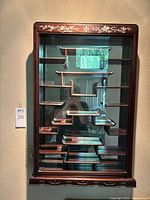 Front view of cabinet showing glass door, mirrored back, interior shelves