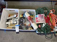Overview of two boxes containing extension cords, rope, tape and other utility items