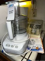 Overall view showing food processor base, bowl, lid, cord, plastic storage case with blades, and manual