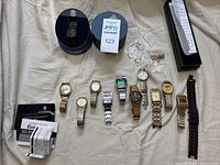 Top view of entire lot showing all watches, watch tins, manuals and presentation box on cloth surface