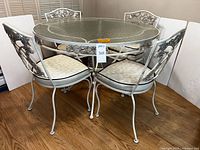 Full view of table and four chairs showing design and cushions