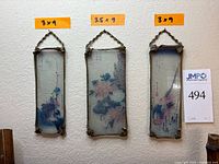 Front view of all three reverse-painted glass panels hanging on wall