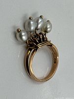 Full view of gold ring showing dangling pearls