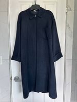 Front view of navy wool coat on hanger showing collar, concealed placket, chest pocket, turn-back cuffs, length