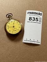 Front view of pocket watch beside lot card