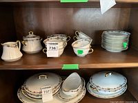 Overall view of dinnerware pieces on two cabinet shelves