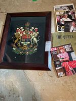 All items laid out: framed crest, stack of magazines, coronation book