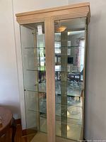 Full view of cabinet showing wood frame, glass door and shelves