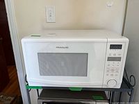 Front view of white Frigidaire countertop microwave showing brand badge, door with window and overall condition