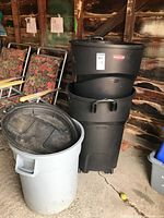 Stack of two black Rubbermaid garbage pails and one light grey pail with lids